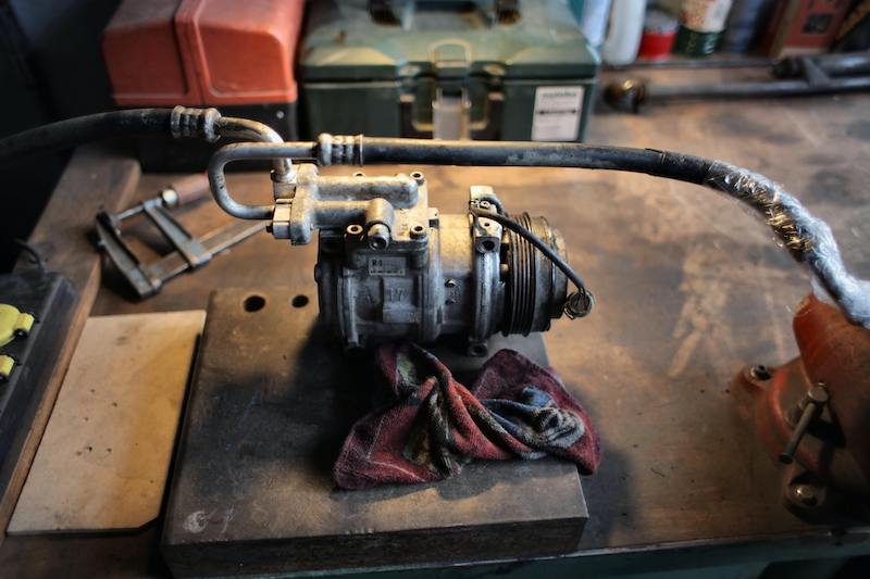 Auto AC Compressor being cleaned and serviced on a work bench