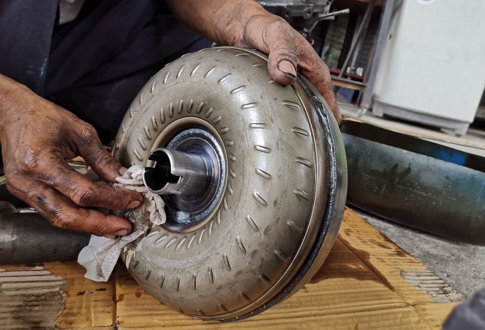 A mechanic cleaning a used torque converter from a Chevy transmission